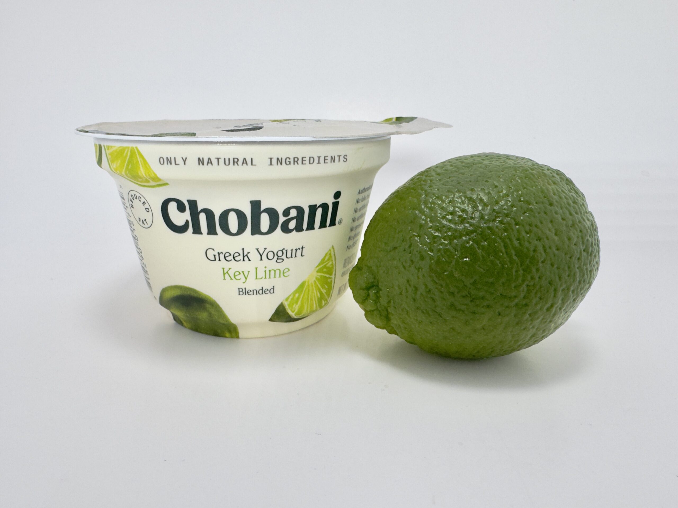 Chobani Greek Yogurt Key Lime Blended cup shown next to a whole, fresh green lime.