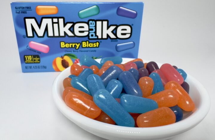 A white bowl filled with assorted Mike and Ike Berry Blast candies in front of the blue theater-sized box.