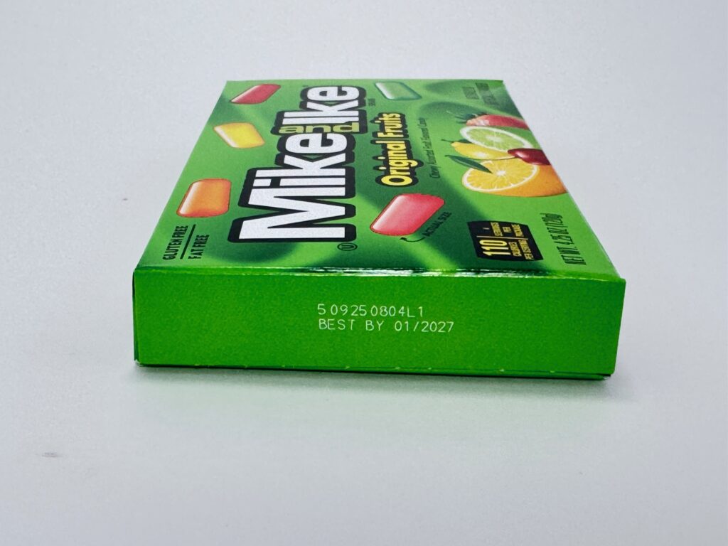 Close-up of the best by marking on a Mike and Ike theater box showing best by 01/2027.