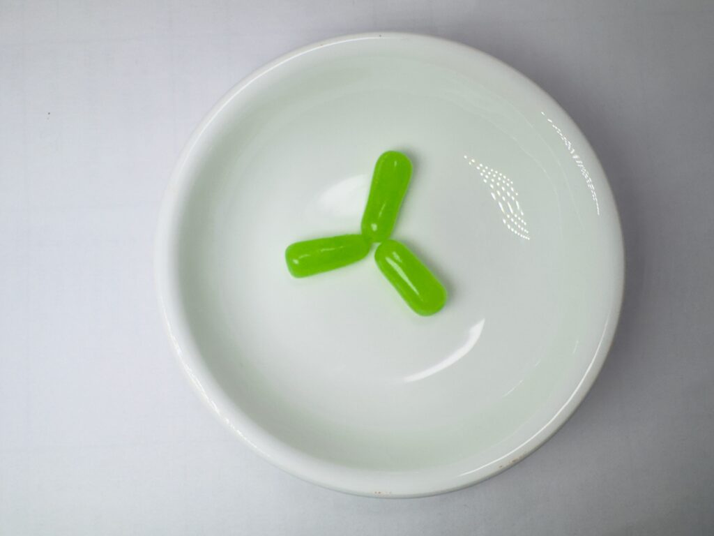 Three bright green Lime flavored Mike and Ike candies in a white bowl.