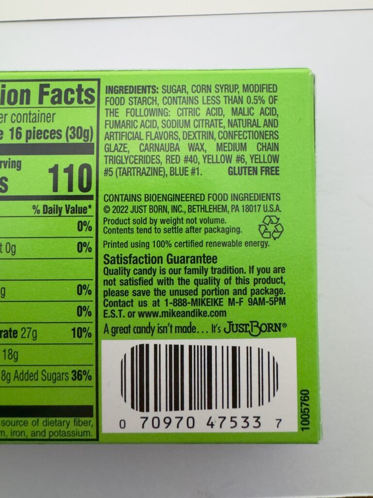 Close-up of the ingredients list on a Mike and Ike Original Fruits box, featuring sugar, corn syrup, and fruit flavors.