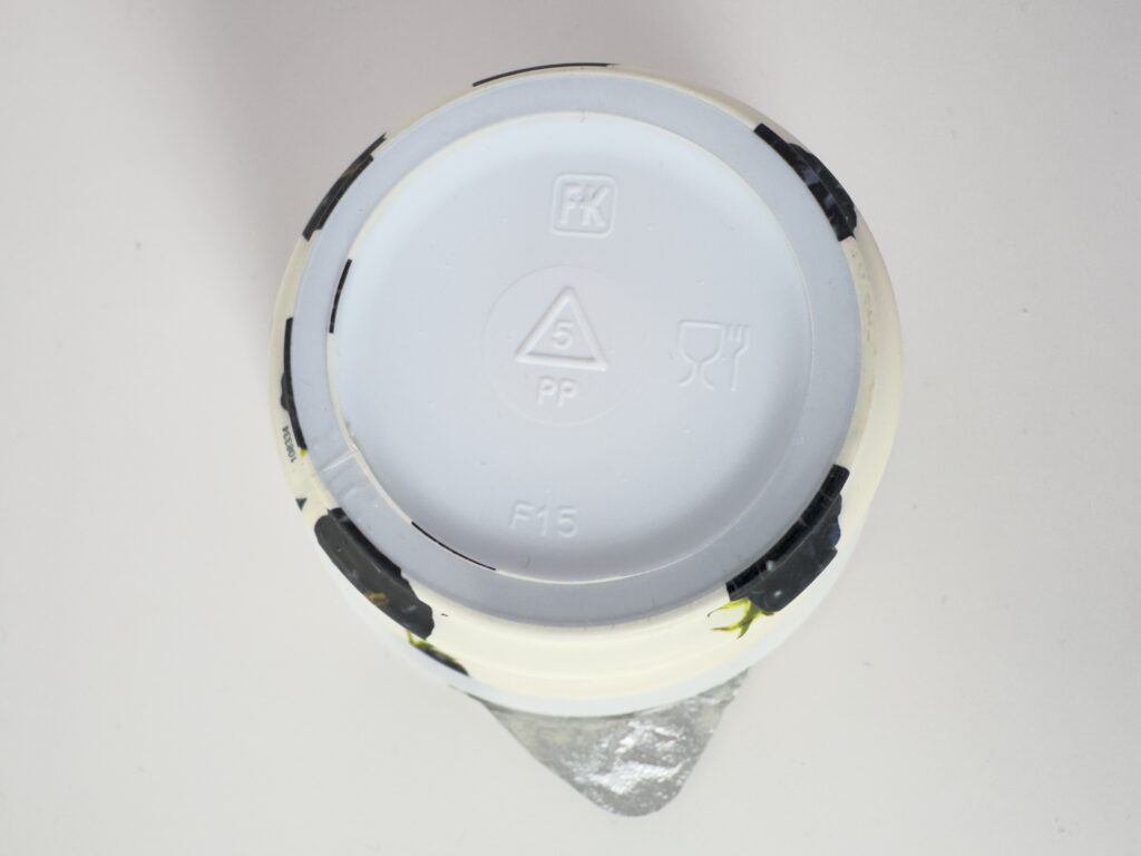 The bottom of a Chobani Greek Yogurt cup showing the number 5 PP recycling symbol and food-grade material icons.