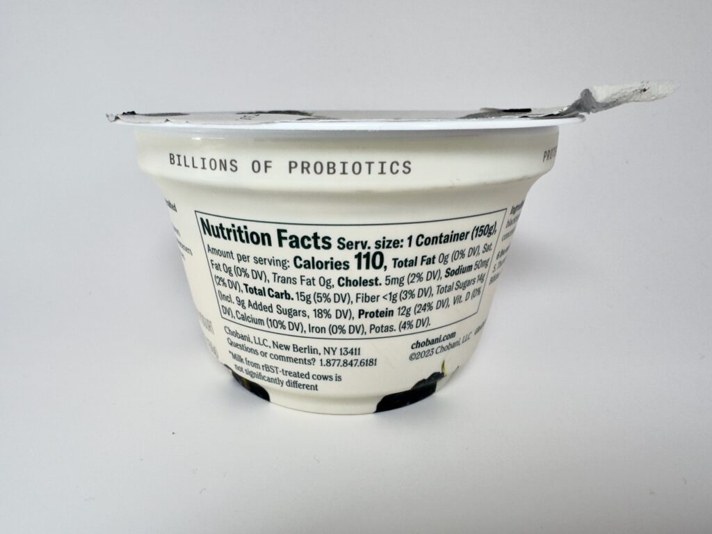 Close-up of the Nutrition Facts label on a Chobani Blackberry Greek Yogurt cup, showing calories, protein, and sugar content.