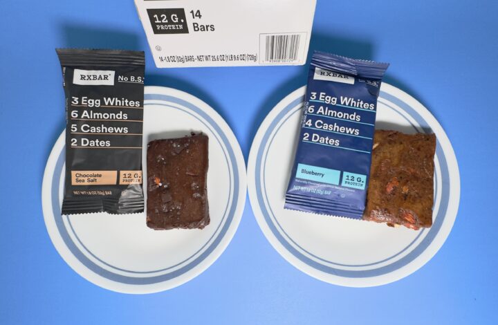 A 14-count variety pack of RXBARs from Costco featuring Chocolate Sea Salt and Blueberry flavors, with two unwrapped bars displayed on white plates.